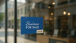 © Shehzad - A blue sign hanging on a glass storefront window with blue rectangular sign hangs clear shop window text indicating business sale entrepreneurship announcement retail