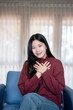 © bongkarn - Asian Woman Holding Hands on Chest Feeling Grateful at Home