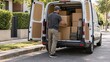© Рудой Максим - Delivery person loads boxes into van on a street lined with trees and homes in daylight