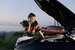 © SHOTPRIME STUDIO - Curious woman with colorful sweater inspecting a car hood on a roadside at sunset, outdoor scene suggesting vehicle trouble and calm determination.