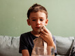© B Krokodil/Stocksy - Sad Injured Boy Sitting on Sofa Holding a Towel with Ice on his Face