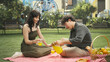 © DC Studio - Young couple pouring orange juice into glasses before making cheerful toast during romantic picnic date, enjoying eye contact, leisure and quality time.
