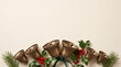 © Sabbir - Charming Christmas holiday background featuring antique brass bells, green ribbon, holly leaves, red berries, and pine branches arranged along the bottom border on a soft cream surface with