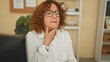© Krakenimages.com - Woman touching throat at computer in building, seated at desk with watch and glasses, appearing to cough or check her sore throat; health concern.