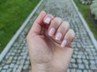 © ooolga32 - Close up of woman hand with elegant natural French manicure. Female fingers with neat clean fingernails on blurred background of cobblestone walkway in the park. Beauty, body care and lifestyle concep