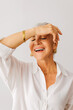 © BONNINSTUDIO/Stocksy - Senior woman shielding eyes and laughing happily