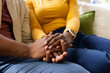 © Wavebreak Media - Joined hands and forearms are resting on living room couch with rose-gold smartwatch, denim