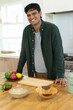© Wavebreak Media - Indian man leaning on butcher-block countertop, preparing meal with cutting board, peppers, herbs