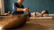 © LenaLensLife - Traditional singing bowl sound healing therapy with practitioner and reclining client in a tranquil holistic wellness setting