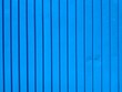 © Elena - Full frame horizontal shot of a bright blue corrugated metal surface with clean vertical lines and a minimal industrial texture.