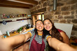 © Alvaro Lavin/Stocksy - Smiling women taking selfie in rustic kitchen