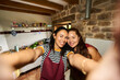 © Alvaro Lavin/Stocksy - Smiling mother and daughter taking selfie in kitchen