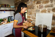 © Alvaro Lavin/Stocksy - Woman cooking fresh vegetables in rustic kitchen