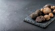 © savittree - Assorted Black Truffles Arranged on Slate Plate with Dark Background for Culinary and Gourmet Concepts