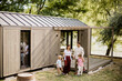 © BGStock72 - Family enjoying a sunny day near a modern cabin by the river