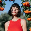 © Andrii Zastrozhnov - Female portrait in red tank top among orange berry branches with delicate leaf shadow for summer fashion background and beauty banner