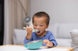 © leungchopan - Little toddler boy eating from bowl with spoon