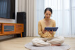 © leungchopan - Woman sitting on floor using digital tablet computer at home