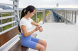 © leungchopan - Sport woman sitting on bench checking smart watch