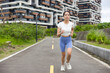 © leungchopan - Woman running on path with buildings in park