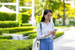 © leungchopan - Woman standing near green garden hedge looking at smartphone