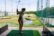 © leungchopan - Woman swinging golf club at outdoor driving range