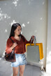 © leungchopan - Woman carrying shopping bag standing by wall in taiwan