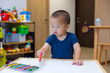 © leungchopan - Toddler boy holding crayon drawing on paper at table