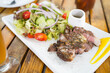 © leungchopan - Close up of sliced grilled steak and fresh salad on wooden table