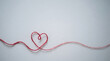 © NurAiniDewi - Red yarn formed into a delicate heart shape rests against a smooth light background to symbolize affection, romance, and emotional connection.