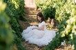 © sanul - Young woman in white dress sitting in vineyard