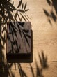 © Ari - Leather-bound journal on rustic wooden table with soft dappled leaf shadows, gentle natural lighting creating calm and serene writing atmosphere
