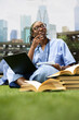 © DC Studio - Medical student, notebook and thinking as a learner in scrubs pauses with pen at the chin beside a laptop. Reflection, problem solving and learning support study planning on a grassy campus lawn.