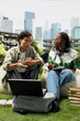 © DC Studio - Students, laptop and discussion as peers exchange ideas beside books and notes on beanbags. Collaboration, peer learning and academic planning connect study partners on a grassy campus lawn.