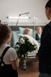 © DC Studio - Flowers, hospital and visit with a girl holding a white bouquet as she approaches a senior patient in bed beside an adult visitor, for family support, kindness and a thoughtful bedside gesture.