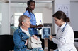 © DC Studio - Imaging, patient and consultation in clinic as a doctor explains a medical scan to an older woman while a nurse records notes, for diagnosis, education, care coordination and treatment planning.