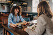 © Ljustina - Smiling woman enjoying breakfast with friend in restaurant