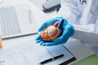 © Charlie's - Cardiologist Explaining Heart Health and Holding Anatomical Heart Model During Medical Consultation in Modern Clinic.