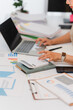 © Wicitr - Focused Accounting: A diligent individual meticulously analyzes financial data using a laptop and calculator, surrounded by reports and charts.
