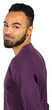 © fotofabrika - Young man with beard poses for a portrait wearing a purple sweater, looking over his shoulder and smiling softly