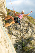 © prelevicm - Girls climbing a rock face outdoors with a rope, helmet, and safety harness