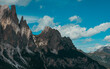 © Vic - Imponenti pareti rocciose e cime frastagliate sovrastano pendii boscosi, sotto suggestive nubi estive, nei pressi delle Cinque Torri, a Cortina d’Ampezzo, nelle Dolomiti venete.
