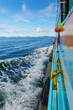 © k33pcalmncapture - Side view of a moving wooden boat with white sea wake and distant islands