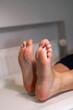 © dsbedarieva - A close-up view shows a client's clean bare feet resting on a couch after a pedicure treatment. The image presents the smooth result of professional salon foot care.