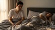 © Maryia - Exhausted partner sitting in bed early morning after sleepless night while other partner rests, realistic bedroom scene showing insomnia effects and fatigue