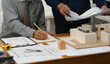 © NINENII - Two architects or civil engineers on blueprint model in corporate office, looking at plans.