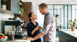 © Celt Studio - Man and woman gazing intimately into each others eyes while drinking coffee near espresso machine in modern workplace kitchen area