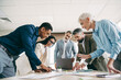 © deagreez - Diverse group of professionals collaborates in a modern office setting, engaging in teamwork and discussing a business project.