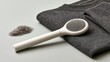© alsu0112 - Fabric lint remover with handle beside folded dark knit clothing and loose fibers on a neutral surface, everyday garment care still life