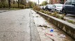 © SashaMagic - Muddy urban runoff flowing through a concrete storm drain beside a sidewalk with plastic debris and litter, illustrating environmental pollution and city infrastructure issues